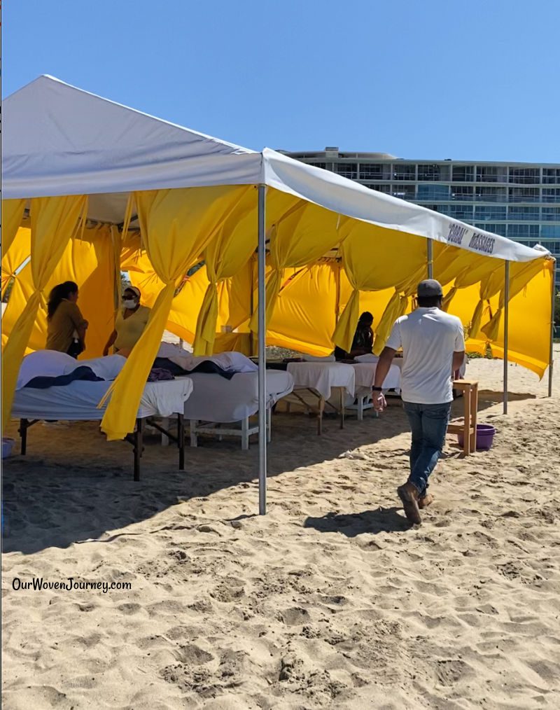 The beach is lined with several tents that have massage tables in them.