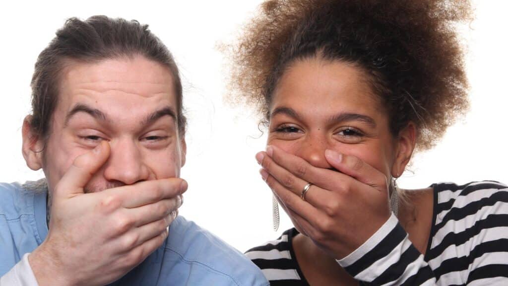 man and woman laughing with hands over mouth