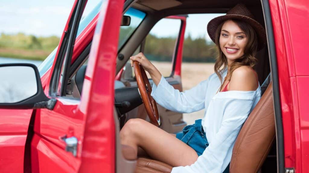 girl sitting in red truck on road trip