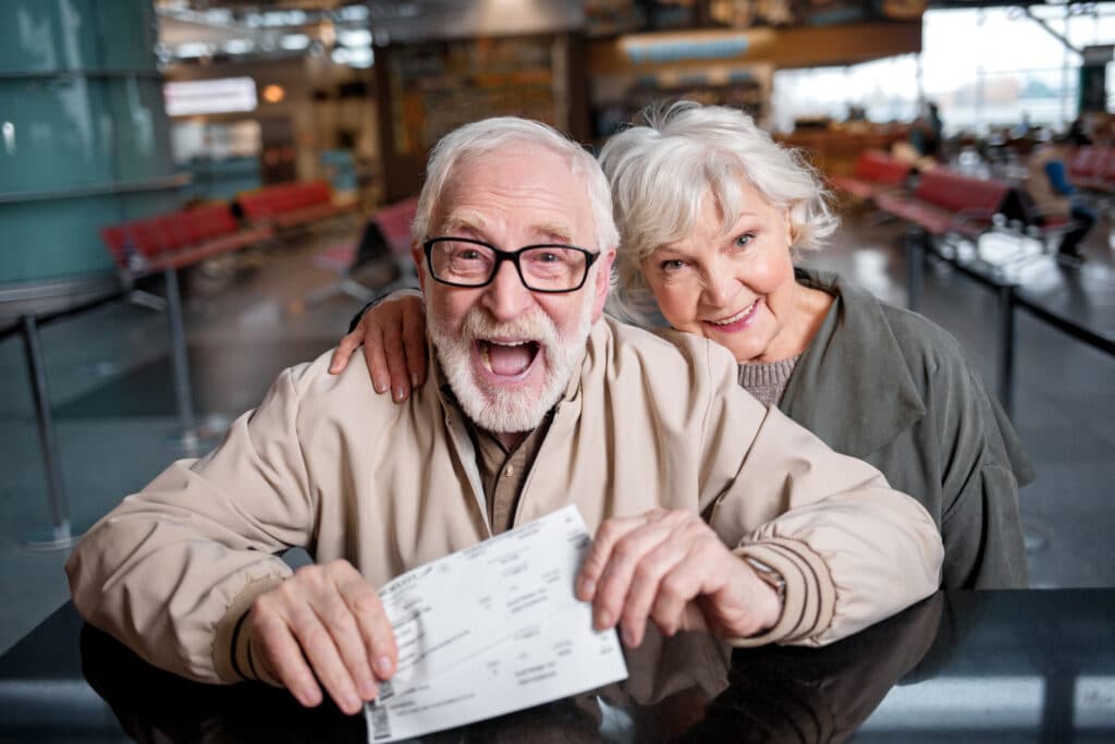 Happy elderly couple are demonstrating their boarding passes with gladness