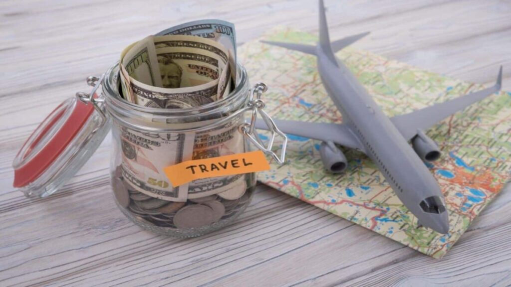 Travel budget concept. Travel money savings in a glass jar with aircraft toy on world map.