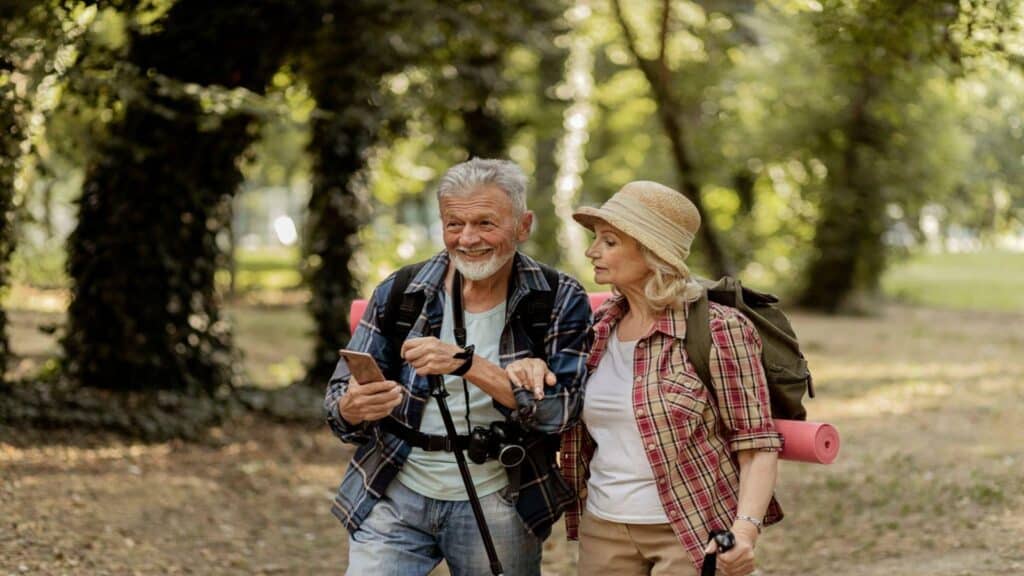 Joyful Senior Couple Travelers Using Smartphone Application Navigation While Hiking in Nature Hiking Adventure Travel People Living Ac