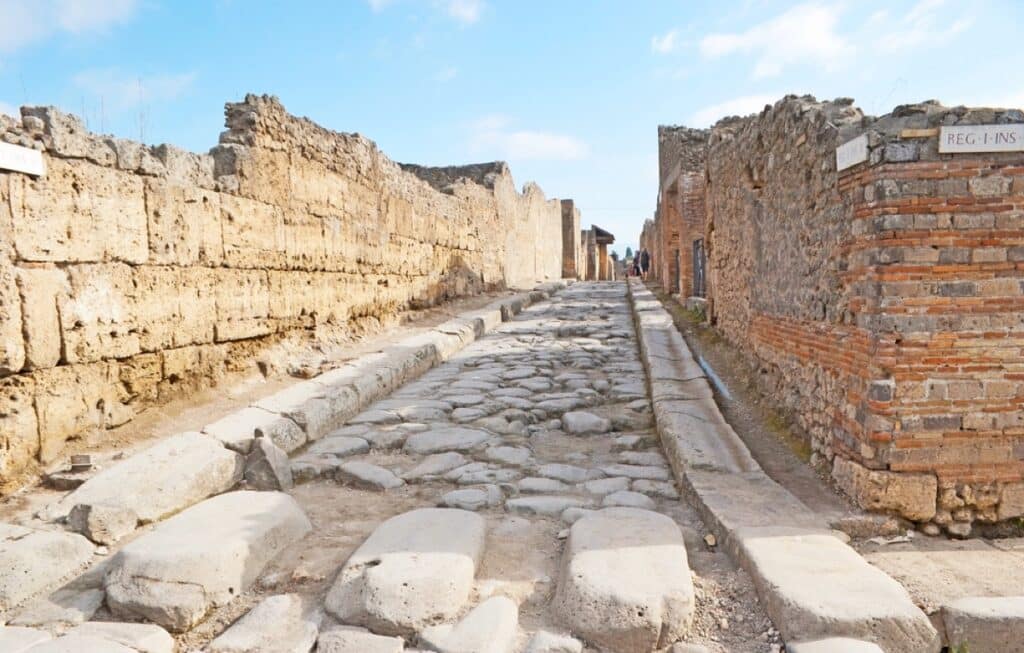 The ancient road in Pompeii covered with paving stone and the large boulders served for pedestrians to cross the street, Italy.
