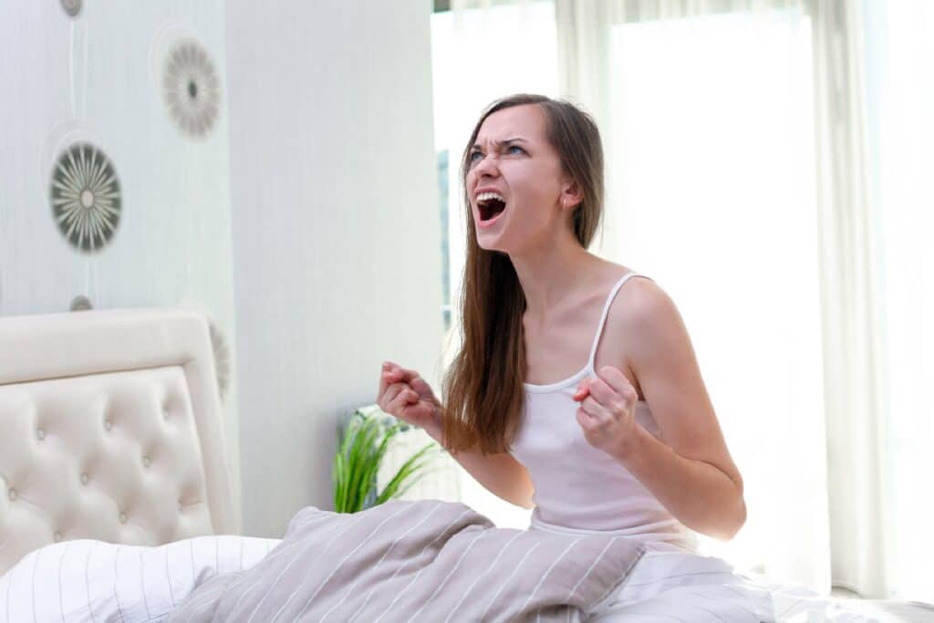 Angry screaming woman suffering and disturbed from noisy neighbors and trying to falling asleep in bed at home in early morning. noisy concept