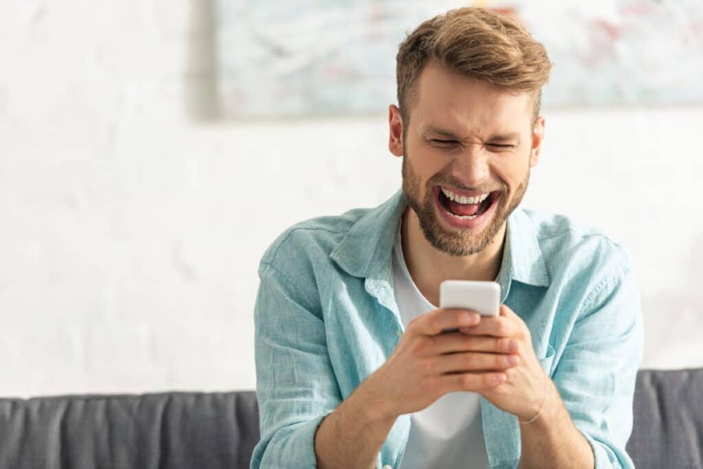 man laughing while texting