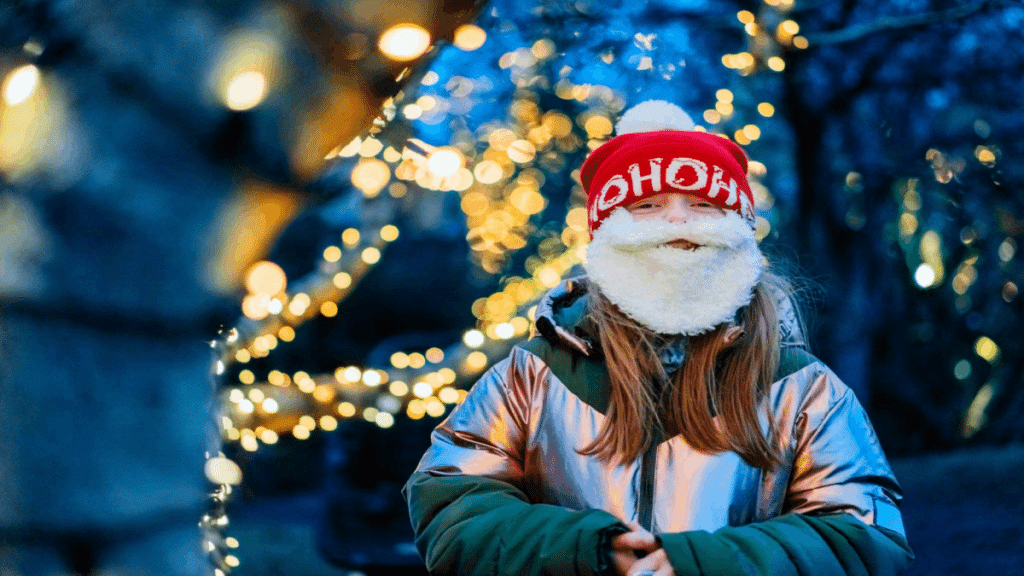 Happy young girl enjoying a walk outdoors dressed like Santa with a beard smiling at camera. Excited for the Christmas holidays