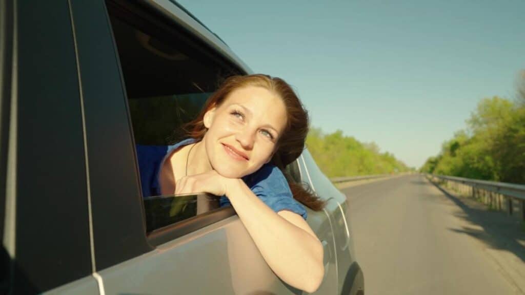smiling woman in car on road trip
