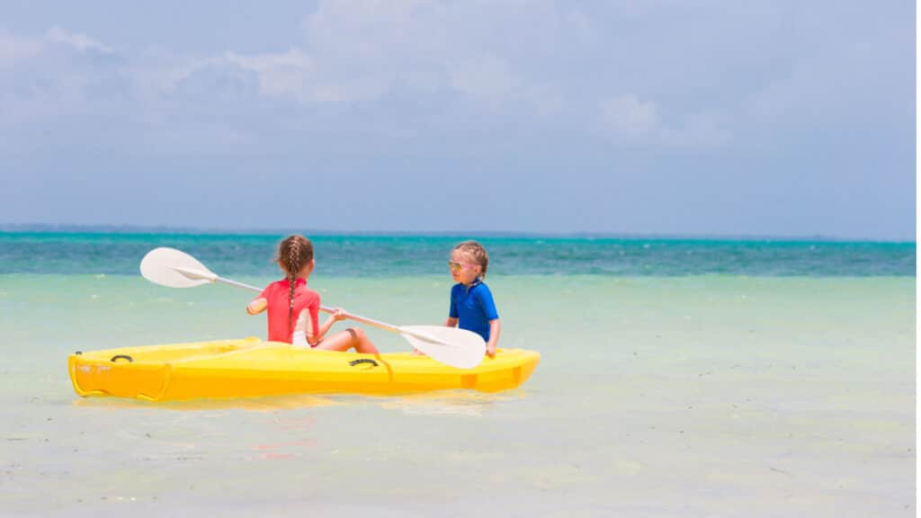 girls in kayak in blue water beach