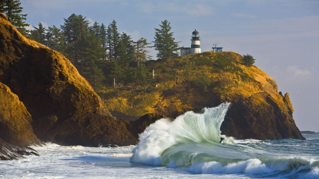 Cape Disappointment Lighthouse on bluff above crashing wave