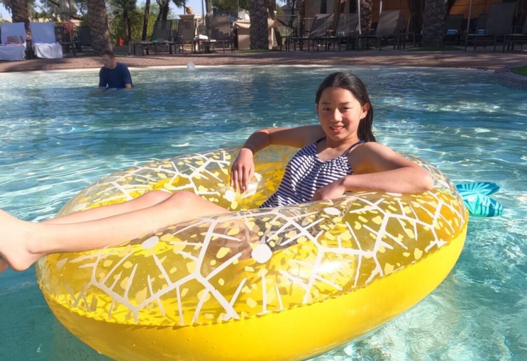 teenage girl on yellow inner tube floating pool